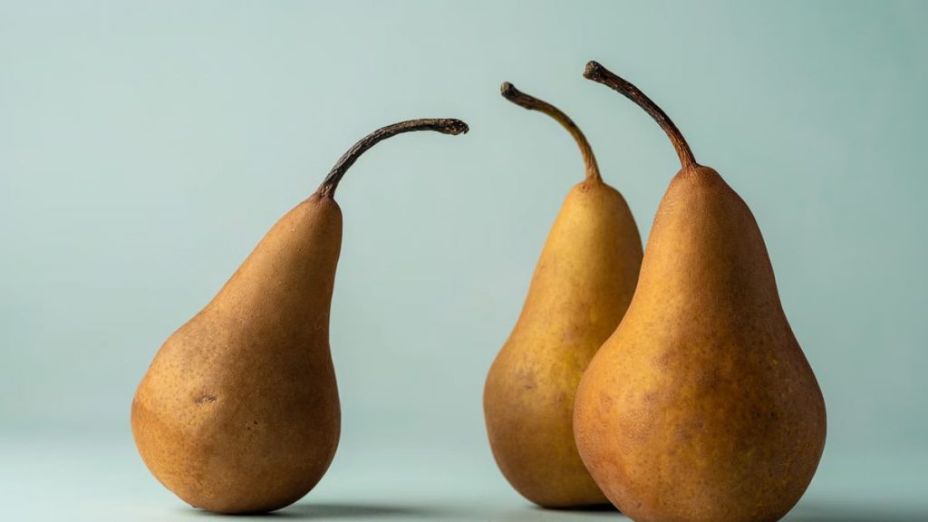 Three ripe pears against a pastel background, highlighting their juicy and nutritious appeal.